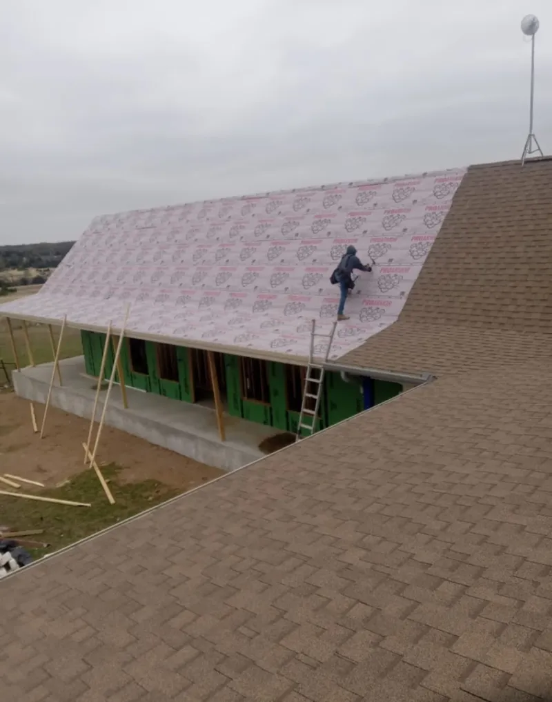 Worker preparing underlayment for a metal roof installation in Gretna